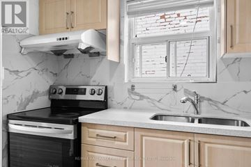 Toronto (North Riverdale) apartment for rent - A kitchen with a black stove top oven and a white range hood.