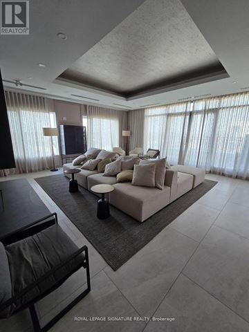 Oakville (Go Glenorchy) condo for rent - A modern living room with a large sectional sofa and a flat screen TV.