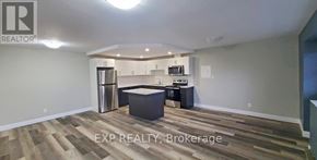 St. Catharines (Vine/Linwell) multi-family for rent - A kitchen area with wooden flooring and a stainless steel refrigerator.