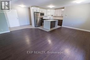 St. Catharines (E. Chester) multi-family for rent - A kitchen with white cabinets and a stainless steel refrigerator.