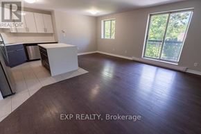 St. Catharines (E. Chester) multi-family for rent - A large empty room with a kitchen area and a window.