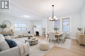 Toronto (Annex) multi-family for rent - A well-lit, spacious living room with a grey sofa, a coffee table, and a dining table set up.