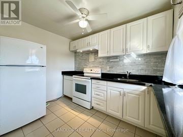 Toronto (Mimico) multi-family for rent - A kitchen with white cabinets and a black countertop.