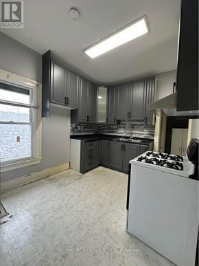 St. Catharines (E. Chester) triplex for rent - A kitchen with a white stove top oven and a window.