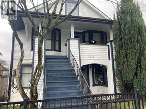 Vancouver apartment for rent - A white house with a black fence and a tree in front.