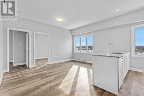 Russell multi-family for rent - A well-lit, empty room with a kitchenette and a large window.