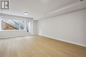 Ottawa apartment for rent - A spacious room with wooden flooring and a large window overlooking a staircase.