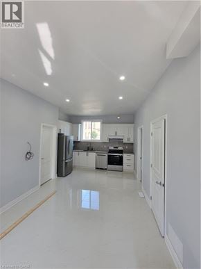 Brantford apartment for rent - A white kitchen with a refrigerator, sink, and cabinets.