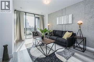 Kitchener condo for rent - A modern living room with a black sofa and a wooden coffee table.