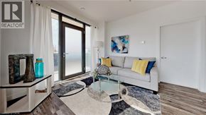 Kitchener condo for rent - A living room with a grey couch, a glass table, and a rug.