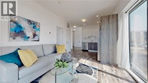 Kitchener condo for rent - A modern living room with a grey sofa and a glass coffee table.