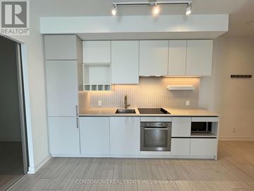 Vaughan (Vaughan Corporate Centre) condo for rent - A kitchen with white cabinets and a black countertop.
