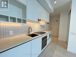 Vaughan (Vaughan Corporate Centre) condo for rent - A kitchen with white cabinets and a tiled backsplash.
