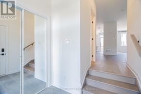 Ottawa townhouse for rent - A white hallway with a staircase and a door leading to another room.