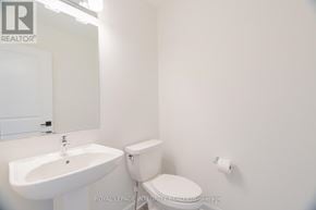 Ottawa townhouse for rent - A white toilet sits next to a white sink in a small bathroom.