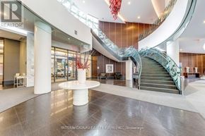 Toronto (Willowdale West) condo for rent - A large atrium with a spiral staircase and a white circular table in the center.