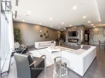 Toronto (Willowdale West) condo for rent - A modern living room with a white sofa set and a stone fireplace.
