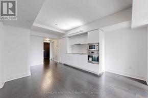 Toronto (Bay Street Corridor) condo for rent - A spacious, empty room with a kitchenette and a framed picture on the wall.