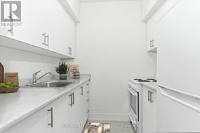 Toronto (Rosedale-Moore Park) condo for rent - A white kitchen with a sink, stove, and cabinets.