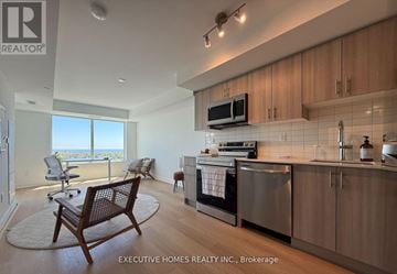 Pickering (Bay Ridges) condo for rent - A modern kitchen with wooden cabinets and a large window overlooking the ocean.