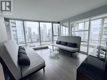 Vancouver apartment for rent - A modern living room with a grey sofa and a glass table.