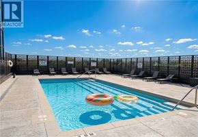 Kitchener condo for rent - A pool with a blue tiled edge and a black fence in the background.