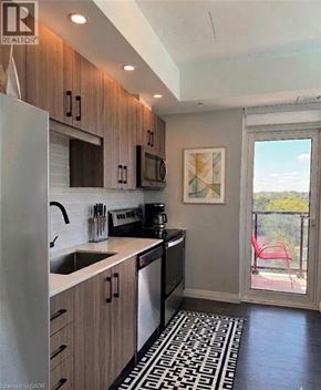 Kitchener condo for rent - A kitchen with a sink, refrigerator, and a window.