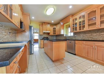 Surrey apartment for rent - A kitchen with wooden cabinets and a black countertop.