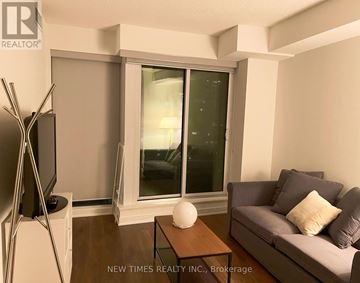 Toronto (Waterfront Communities) condo for rent - A living room with a grey couch, a wooden coffee table, and a television on a stand.