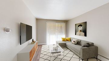 Arvada apartment for rent - A living room with a grey couch, a coffee table, a television, and a painting on the wall.
