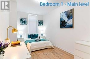 Oshawa (Samac) townhouse for rent - Bedroom 1 on the main level features a bed, a lamp, and a painting.