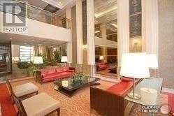 Toronto (Bay Street Corridor) condo for rent - A living room with a couch, chair, and a table with a lamp on it.