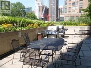 Toronto (Bay Street Corridor) condo for rent - A patio with a table and chairs overlooking a cityscape.