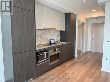 Vaughan (Vaughan Corporate Centre) condo for rent - A modern kitchen with dark wood cabinets and a marble countertop.