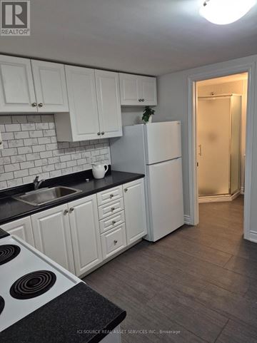Toronto (Bendale) apartment for rent - A kitchen with white cabinets and a black countertop.