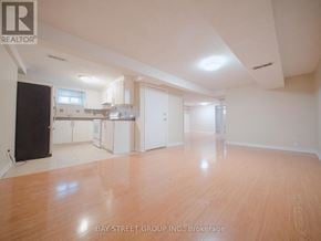 Brampton (Downtown Brampton) apartment for rent - A spacious room with wooden flooring and white walls, with a kitchen area visible in the background.