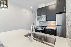 Hamilton condo for rent - A modern kitchen with a stainless steel refrigerator, microwave, and oven.