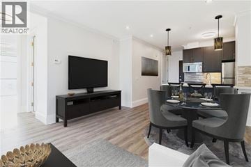 Hamilton condo for rent - A modern living room with a black television and grey chairs.