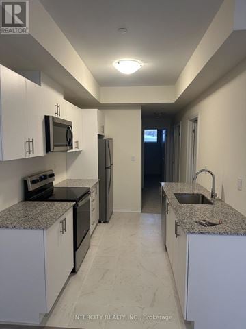 Toronto (Malvern) townhouse for rent - A kitchen with white cabinets and granite countertops.