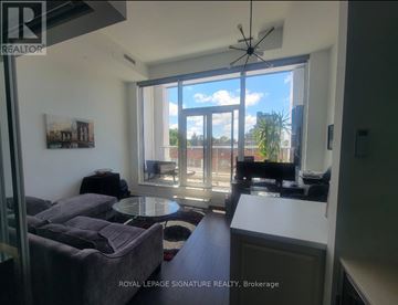Toronto (Humewood-Cedarvale) condo for rent - A living room with a grey couch and a table in front of a large window.