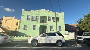 Miami apartment for rent - A green building with a white car parked in front.