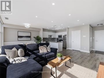 Mississauga (Erindale) condo for rent - A modern living room with a dark blue sofa and a wooden coffee table.