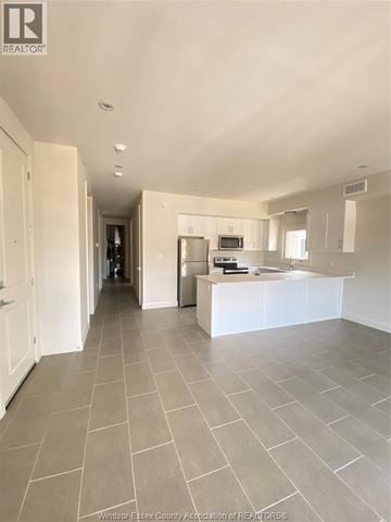 Windsor condo for rent - A spacious kitchen with white cabinets and a central island.