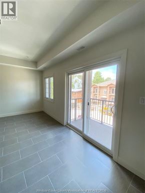 Windsor condo for rent - A room with a sliding glass door leading to a balcony.