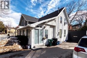 Kitchener apartment for rent - A white house with a grey roof and a car parked in front.