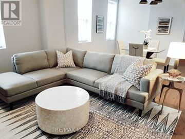 Oshawa (O'neill) multi-family for rent - A living room with a grey couch and a white ottoman.