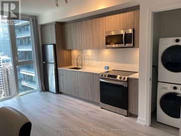 Toronto (Waterfront Communities) condo for rent - A modern kitchen with wooden cabinets and stainless steel appliances.