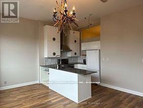 Toronto (Niagara) condo for rent - A kitchen with a white island and a chandelier.