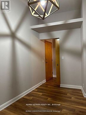 Toronto (Niagara) condo for rent - A hallway with a wooden floor and a light hanging from the ceiling.