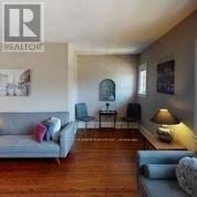 Toronto (Forest Hill South) multi-family for rent - A living room with a grey couch and a wooden floor.